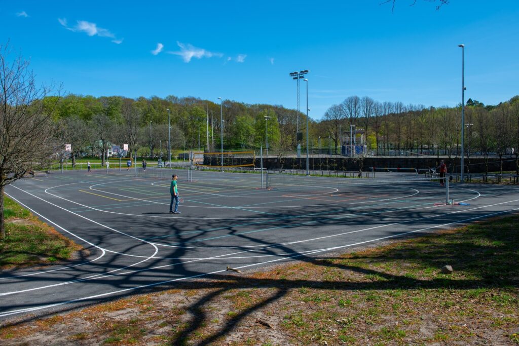 Newly paved asphalt school sports court and multi-use outdoor play area featuring painted running tracks and game lines.