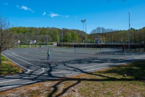 Newly paved asphalt school sports court and multi-use outdoor play area featuring painted running tracks and game lines.