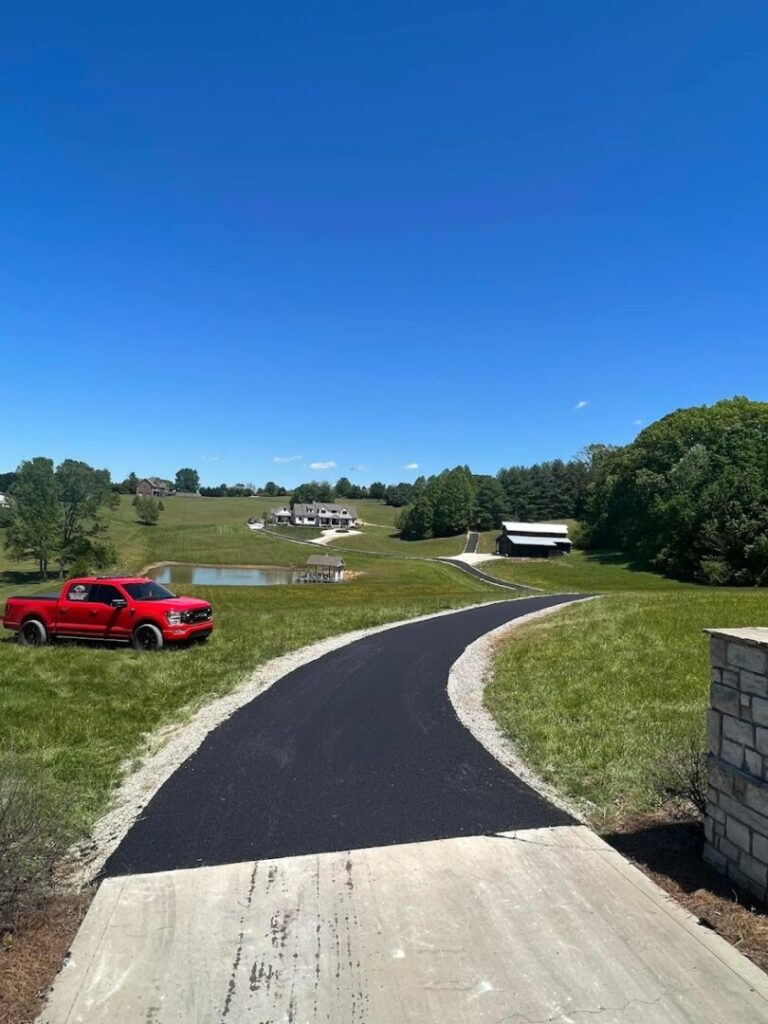 Newly paved blacktop asphalt driveway winding through a scenic green landscape in Powell, TN, completed by Edward's Black Top Paving.