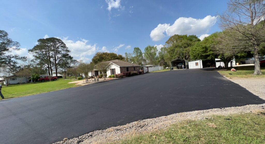 Freshly paved residential blacktop driveway and parking pad outside a home